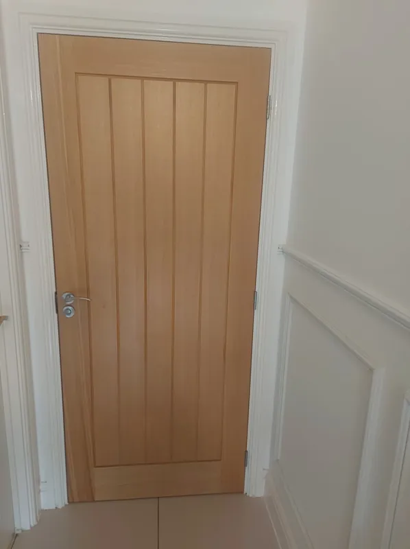 Oak panelled door fitted in a white hallway